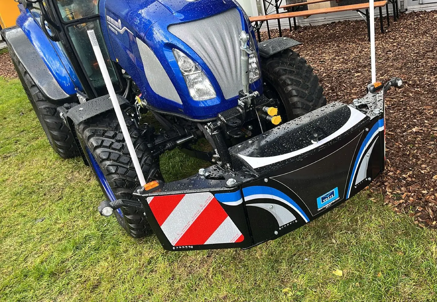 Box CAT 1 front weight bumper mounted on a blue tractor, with reflective markings and rain droplets visible