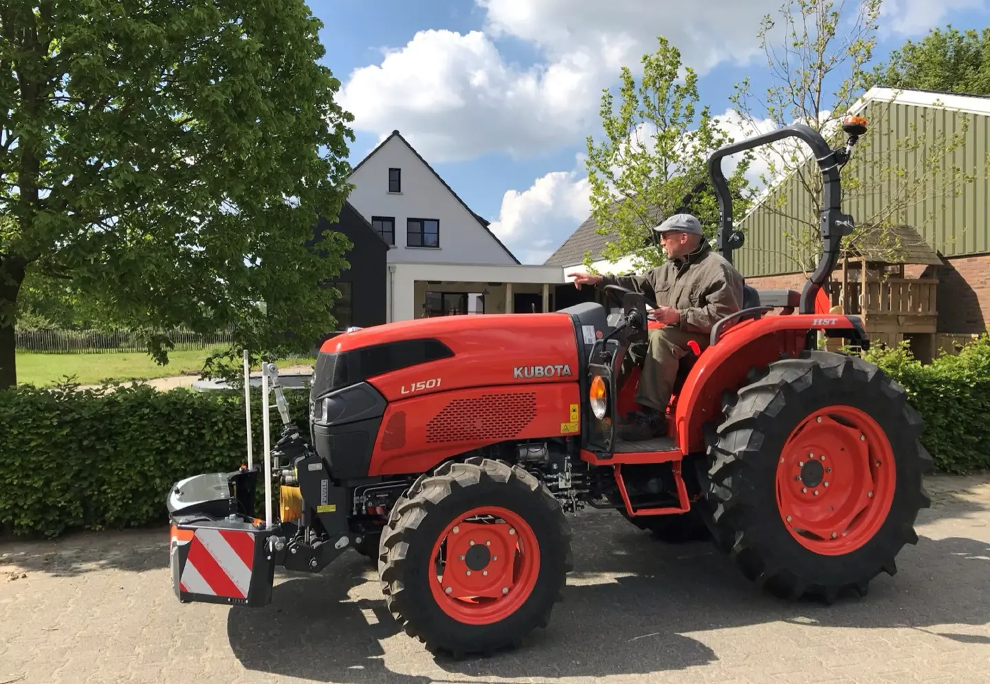 A Box CAT 1 front weight bumper attached to a red tractor with a person sitting in the driver's seat outdoors