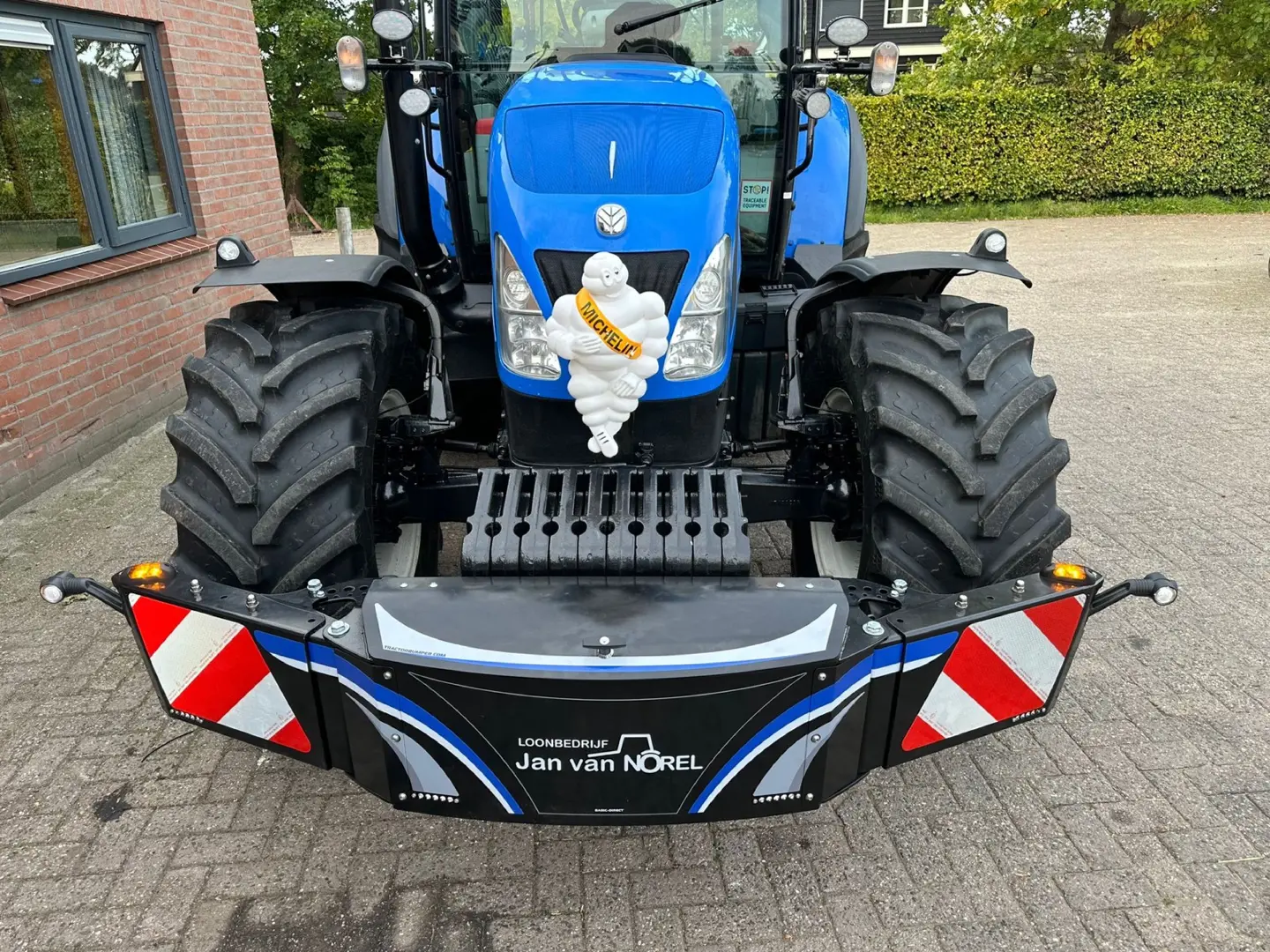 Box 50L without front linkage mounted on the front of a blue tractor with red and white reflective panels