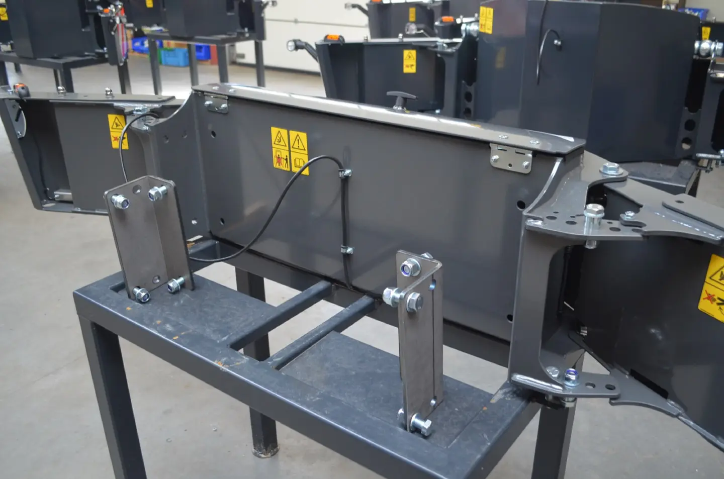 A Box 50L without front linkage is mounted on a stand, showing its attachment brackets and warning labels