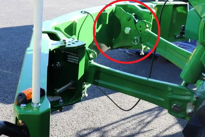 Close-up of a green Connect Direct front weight bumper linkage for tractors, highlighted by a red circle