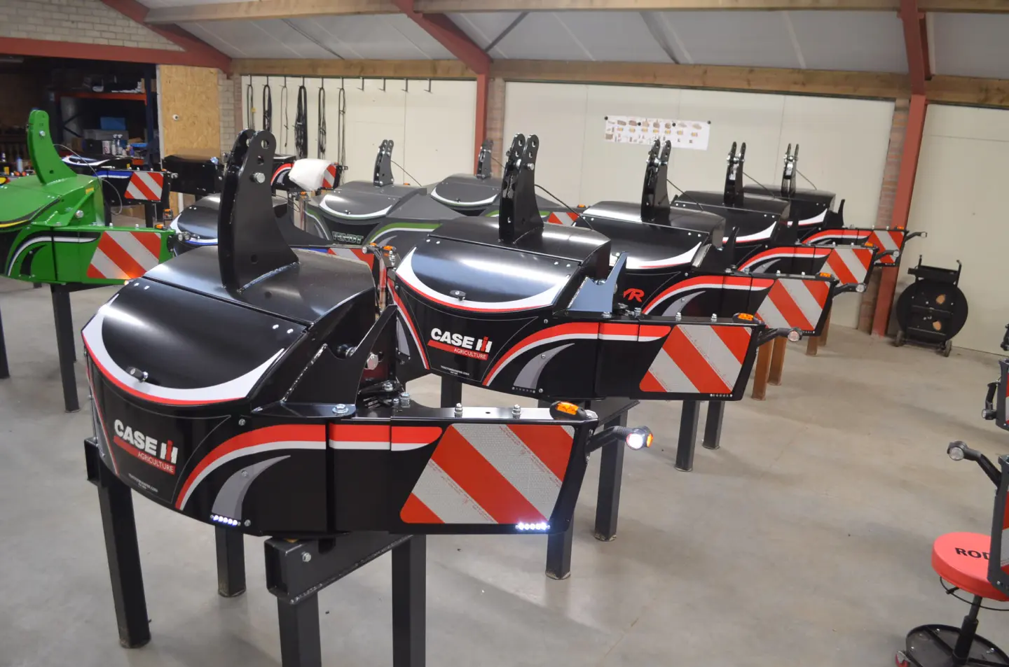 Several black front weight bumpers with red, white and silver striping and CASE IH AGRICULTURE text arranged indoors