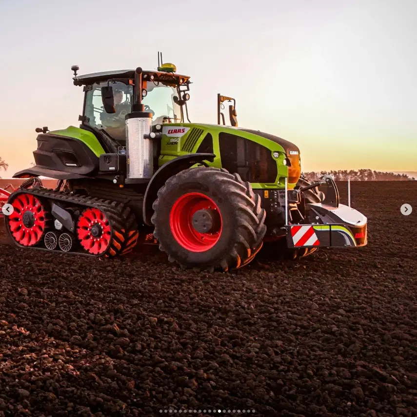 Tracked tractor with a front weight bumper attached, parked on a tilled field at sunset