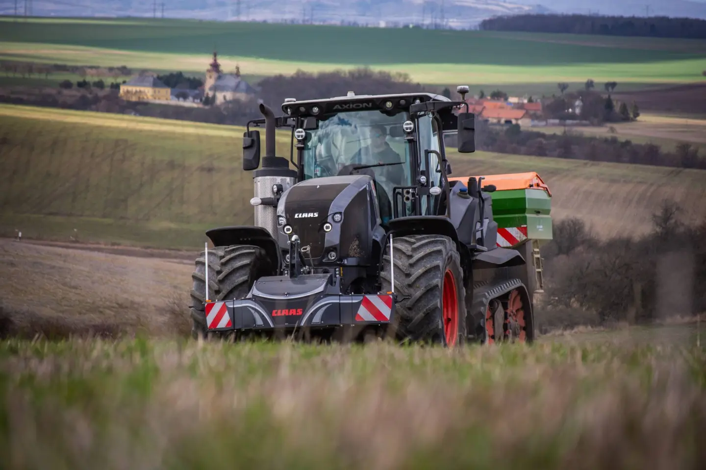 A tractor with a front weight bumper featuring red and white stripes stands in a grassy field.