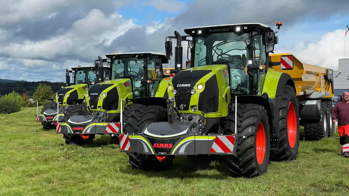 Three green tractors each equipped with front weight bumpers and red-striped safety markings on grass