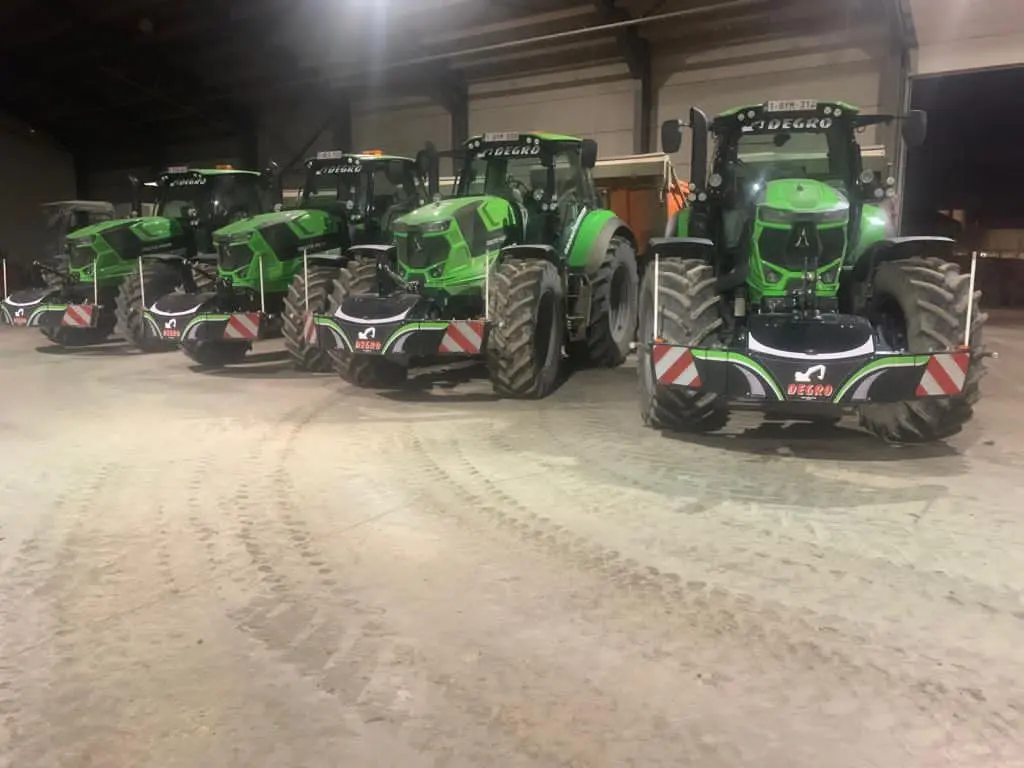 Four green tractors indoors, each equipped with front weight bumpers marked with red and white stripes and Degro logos