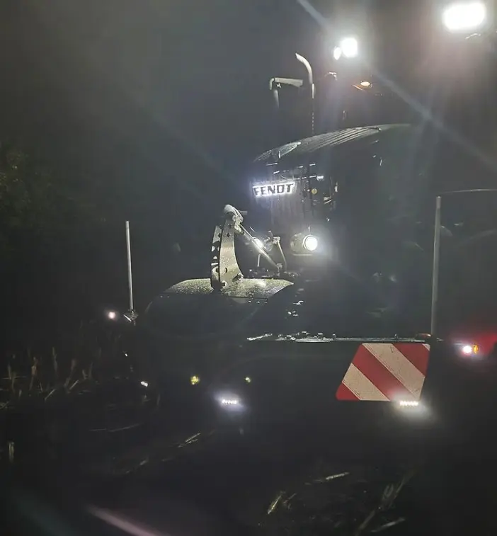 Tractor at night with headlights on, fitted with a front weight bumper featuring reflective red and white stripes