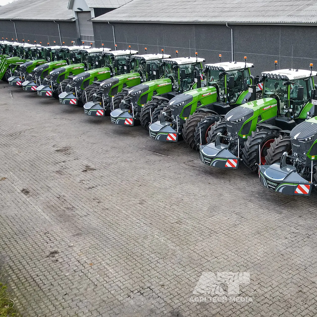 Une rangée de tracteurs verts équipés de grands pare-chocs avant gris avec bandes réfléchissantes rouges et blanches