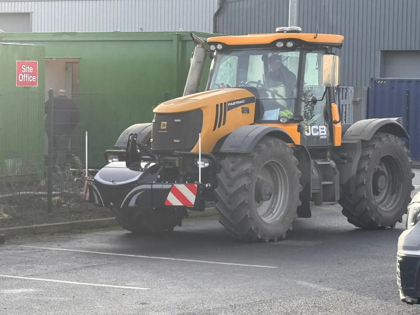 A yellow tractor with large tires is fitted with a black front weight bumper featuring red and white reflective stripes.