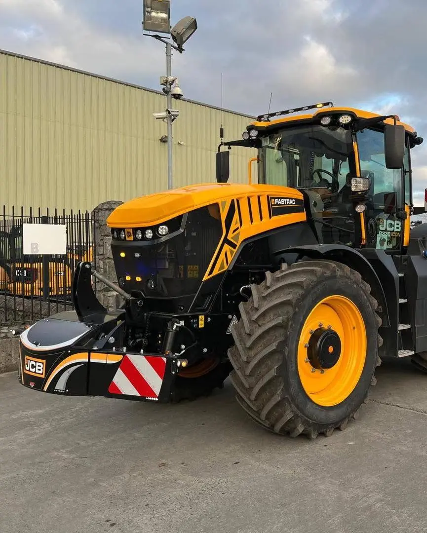 A yellow and black tractor fitted with a front weight bumper featuring reflective red and white stripes