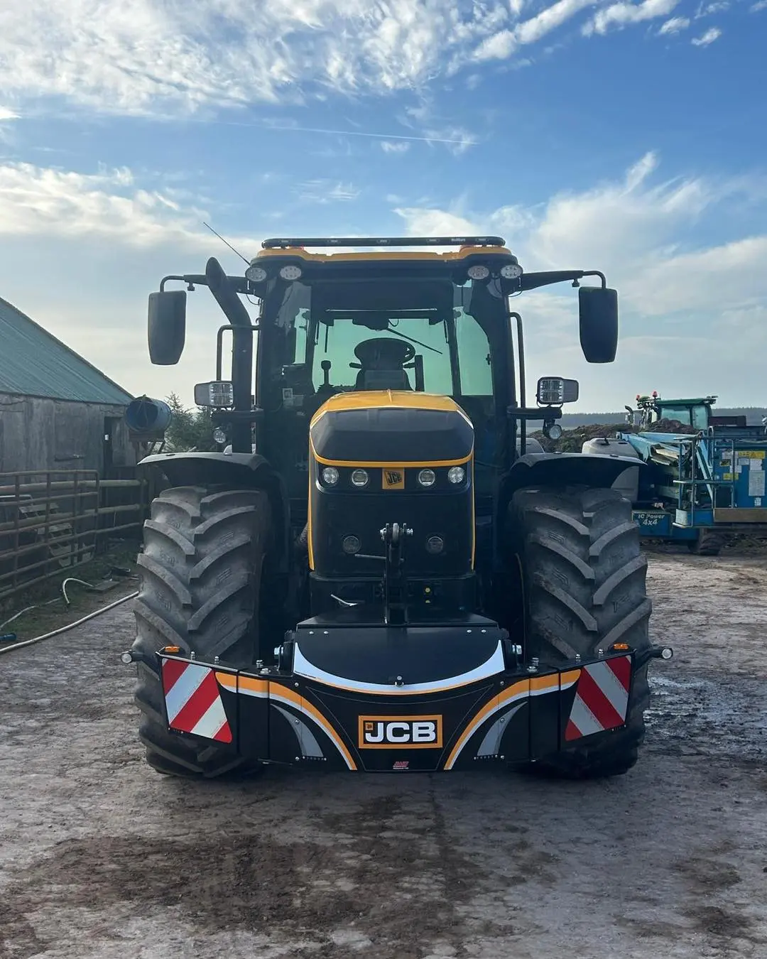 A black and yellow JCB tractor fitted with a front weight bumper featuring reflective red and white stripes