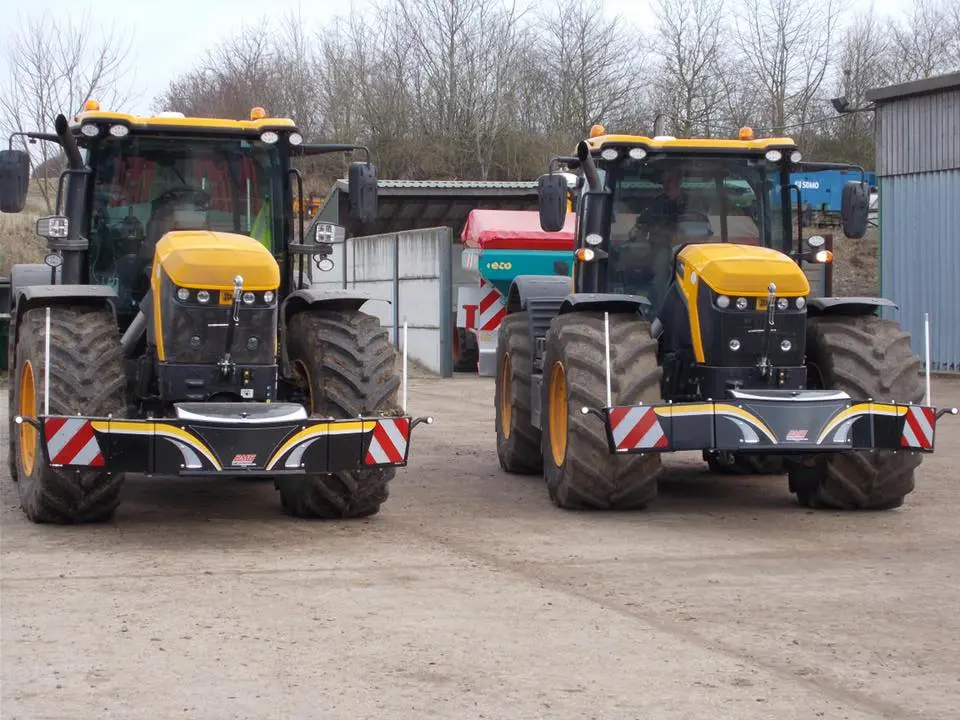 Two yellow and black tractors fitted with front weight bumpers featuring red and white safety markings