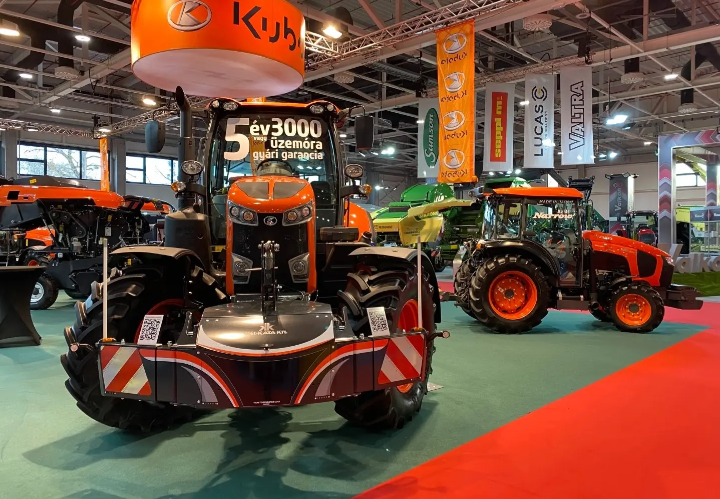Orange tractor on display with a front weight bumper featuring reflective safety markings and a QR code.