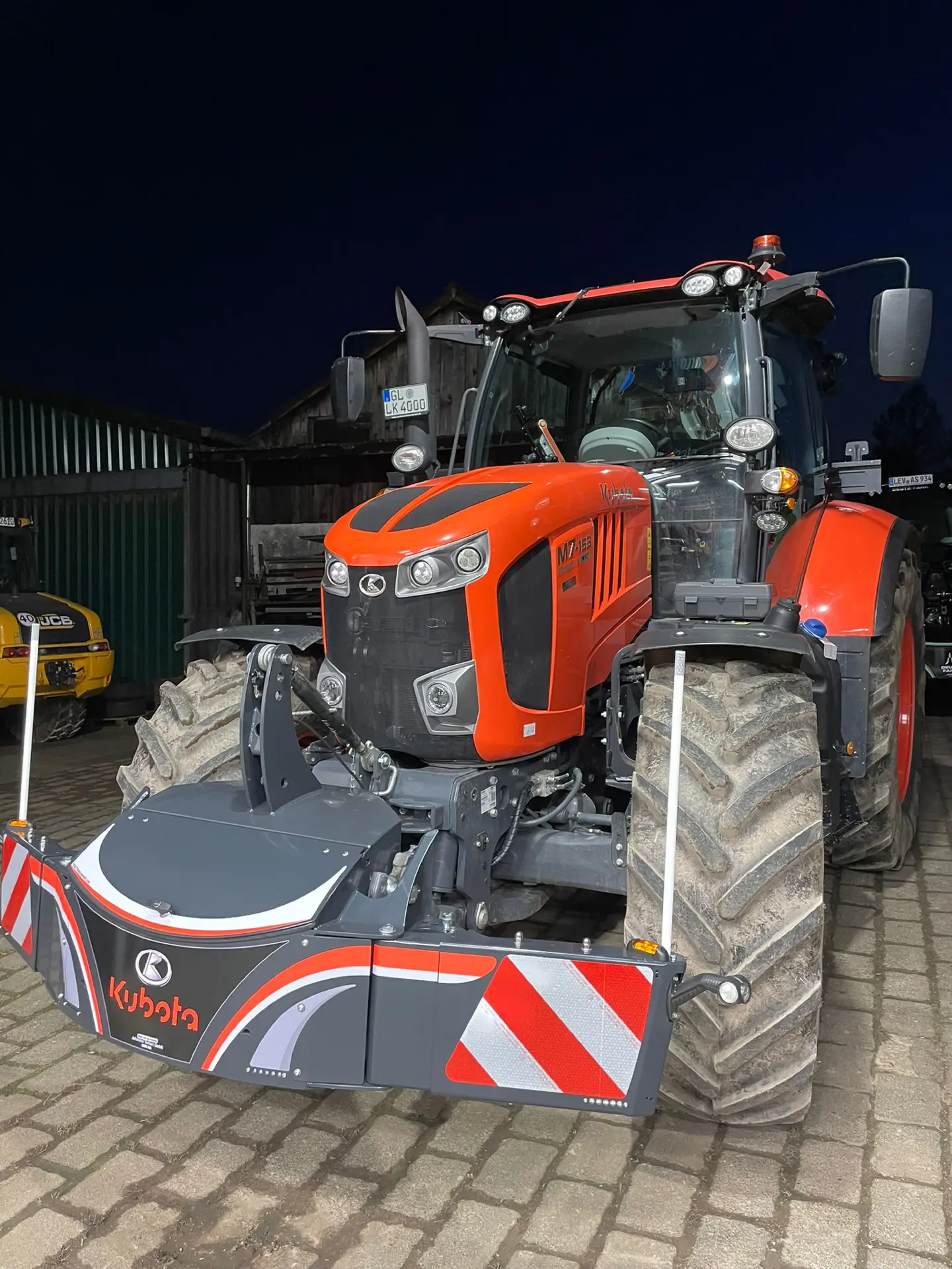 A tractor fitted with a Kubota-branded front weight bumper featuring red and white reflective panels