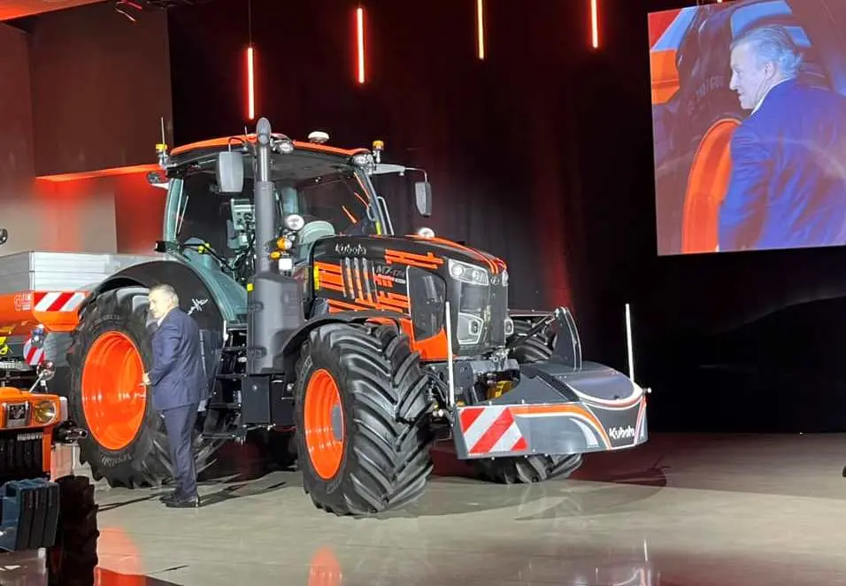 A front weight bumper with red and white safety stripes mounted on a large tractor at an indoor event