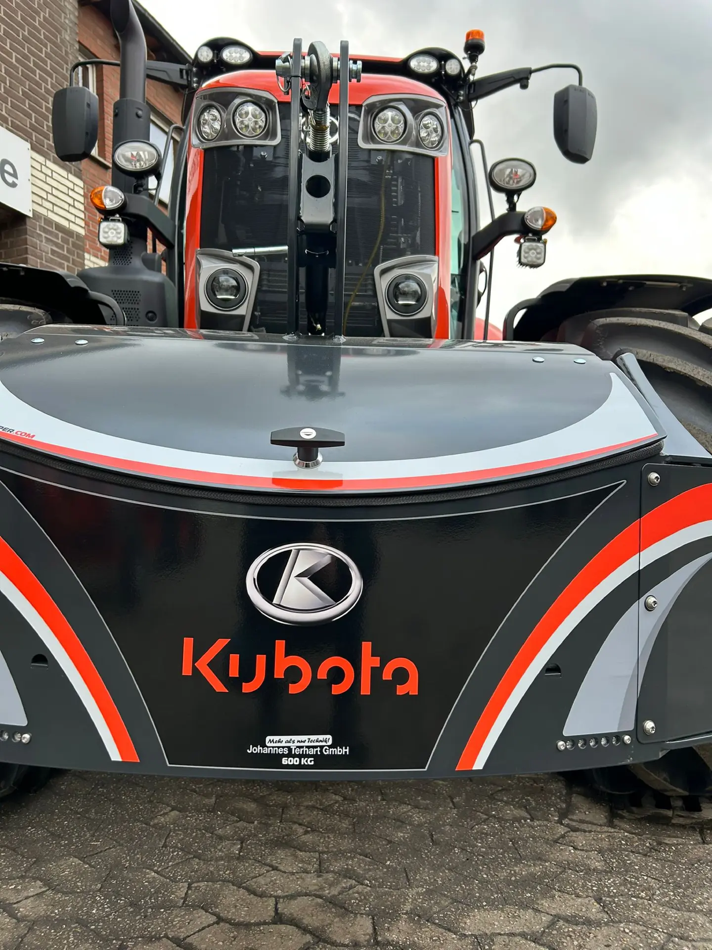 Front view of a tractor with a large black front weight bumper labeled Kubota and marked 600 kg.