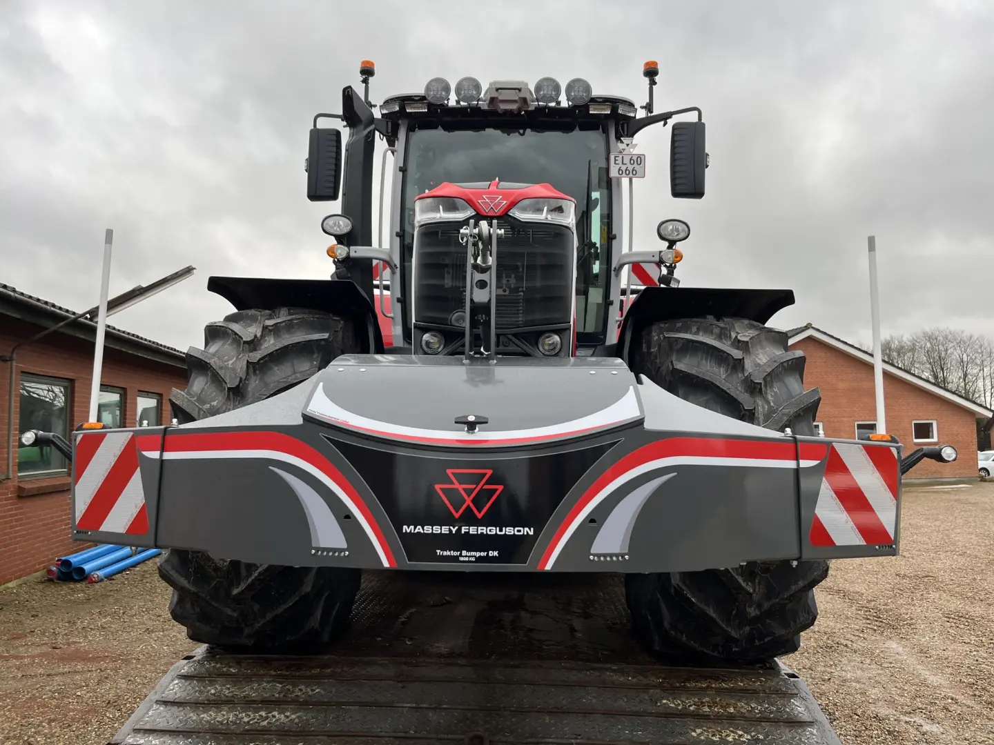 Front view of a large tractor with a gray and red Massey Ferguson bumper weight featuring reflective stripes