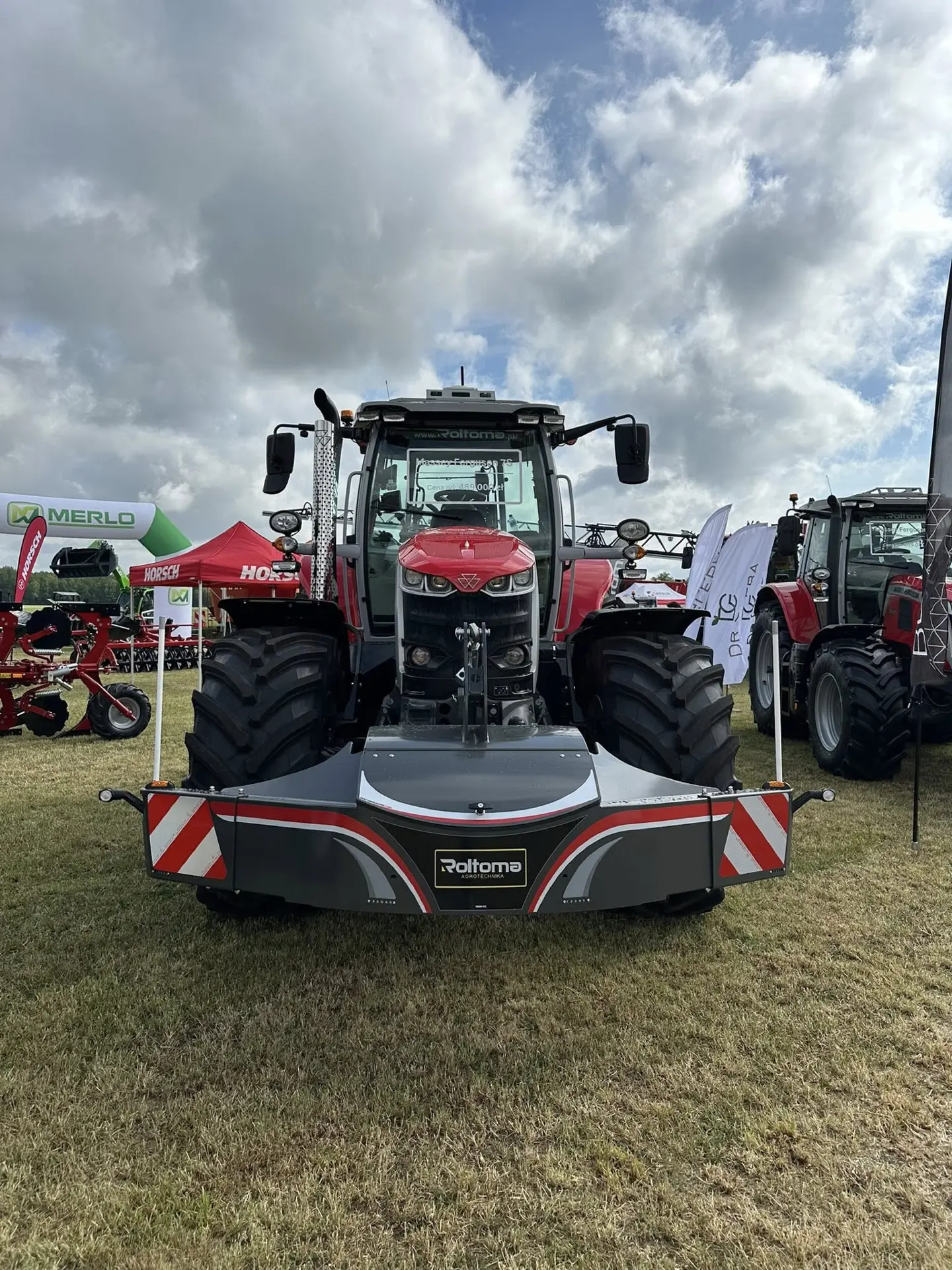 Red tractor with a large black front weight bumper featuring reflective stripes on display outdoors