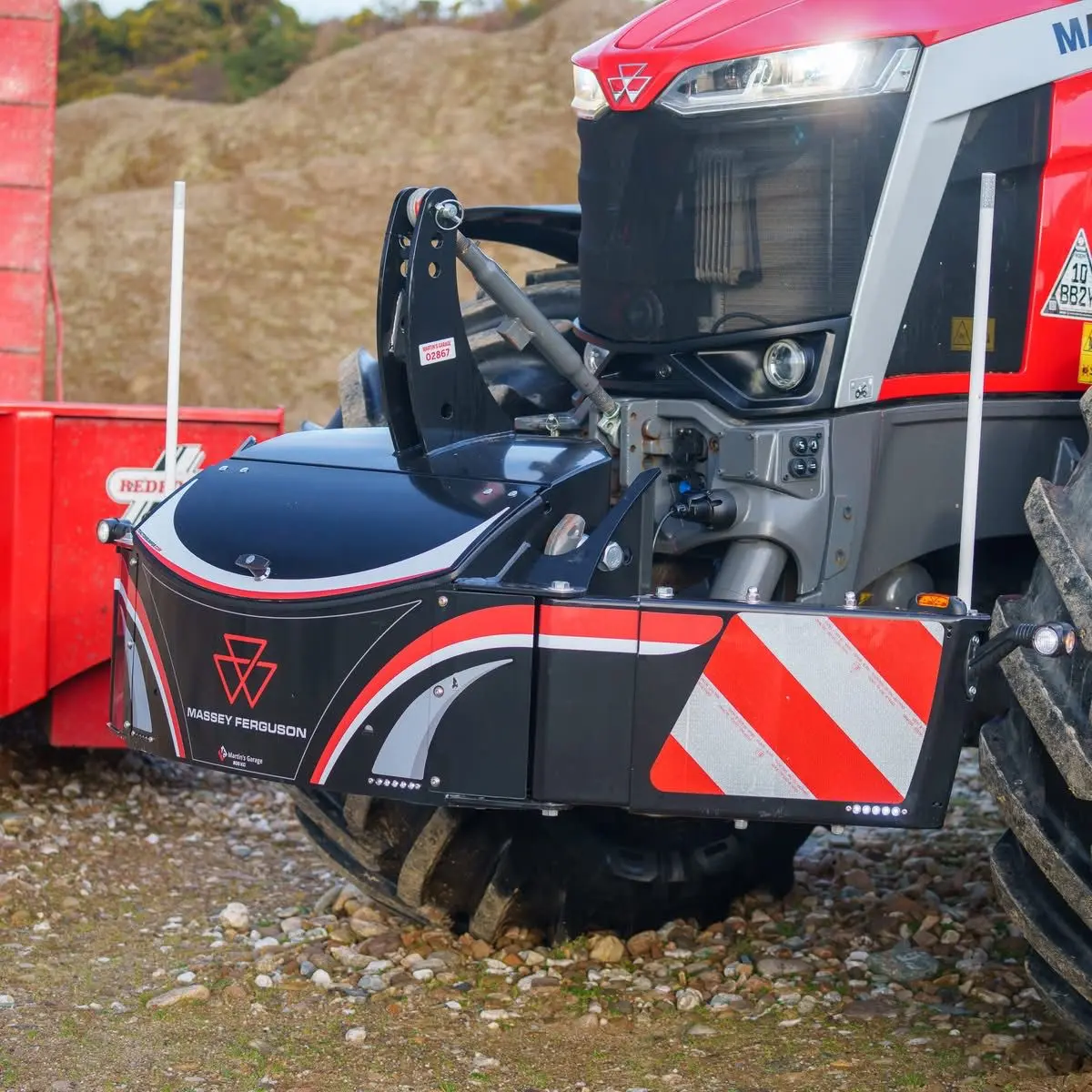 Front view of a Massey Ferguson tractor equipped with a black and red front bumper weight displaying safety stripes
