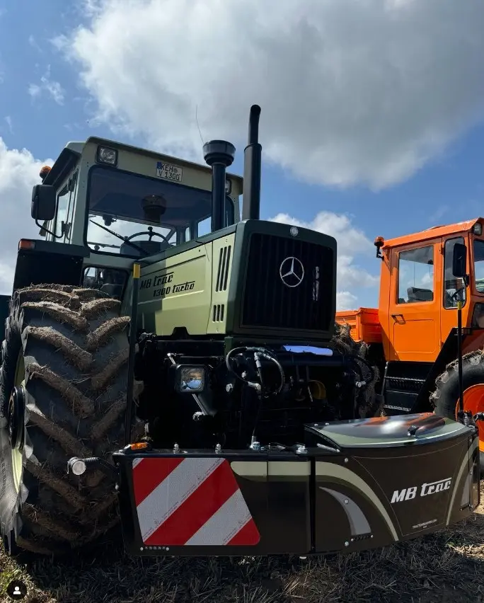Green MB trac tractor fitted with a large front weight bumper featuring red and white reflective stripes and LED lighting