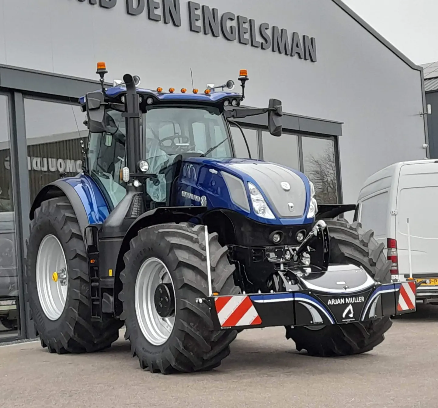 Large blue tractor fitted with a front weight bumper that has red and white reflective stripes and signage