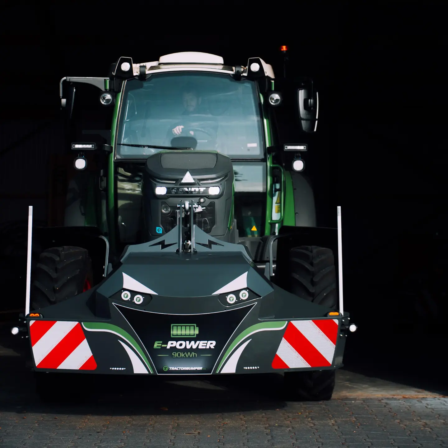 Green tractor with a front weight bumper labeled E-POWER 90 kWh featuring safety stripes and headlight accents