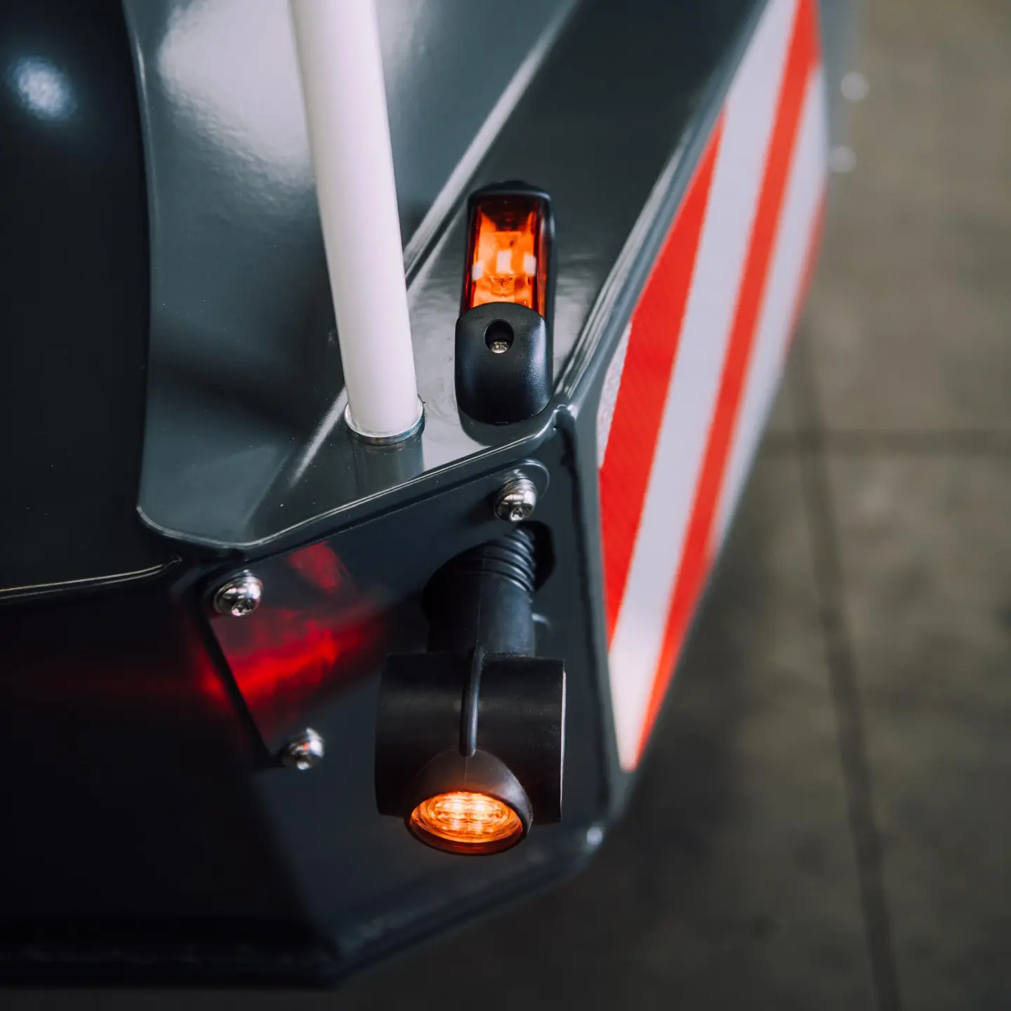 Close-up of a tractor front weight bumper with orange lights and red-white reflective warning stripes