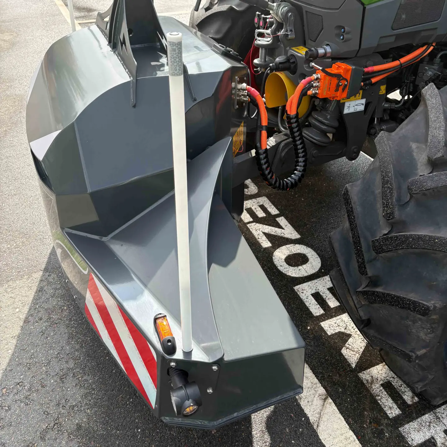 A close view of a heavy-duty front weight bumper attached to a tractor, showing lights and red-white warning stripes