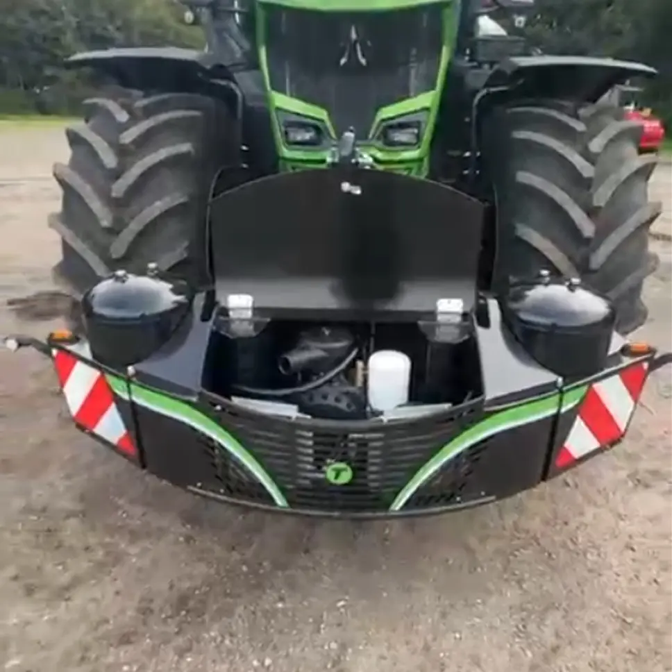 Front view of a tractor with a black and green front weight bumper featuring built-in storage and warning stripes